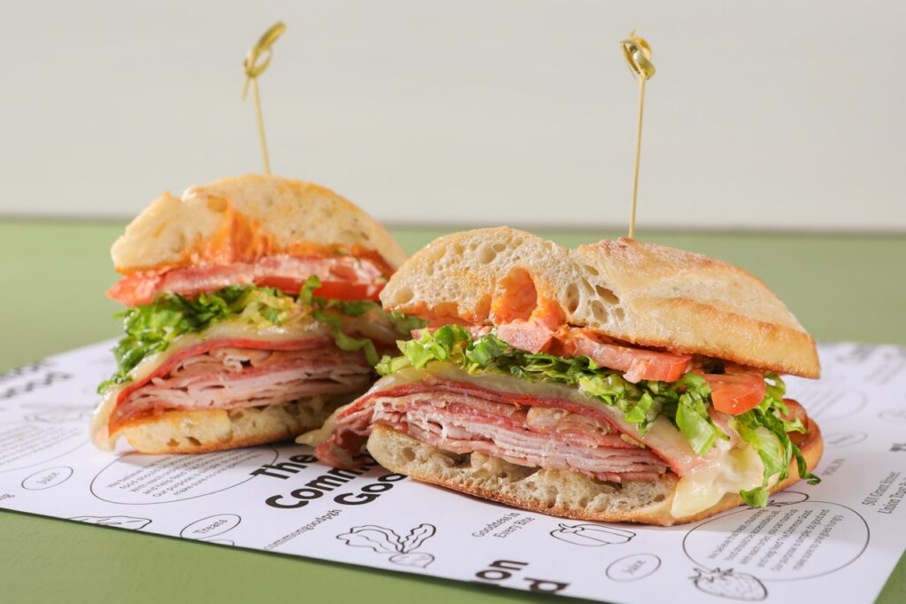 A sandwich with meat and veggies sits broken in half.