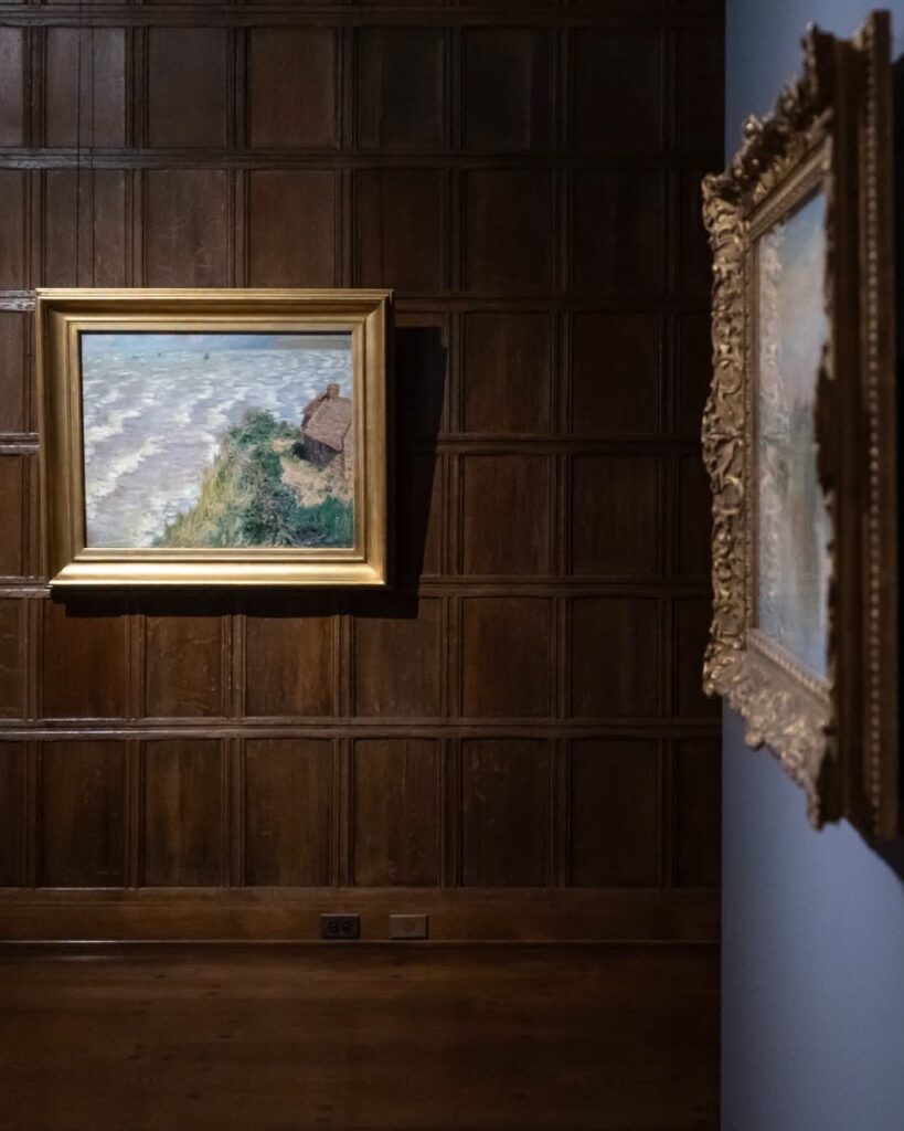 Two paintings on dark gallery walls.