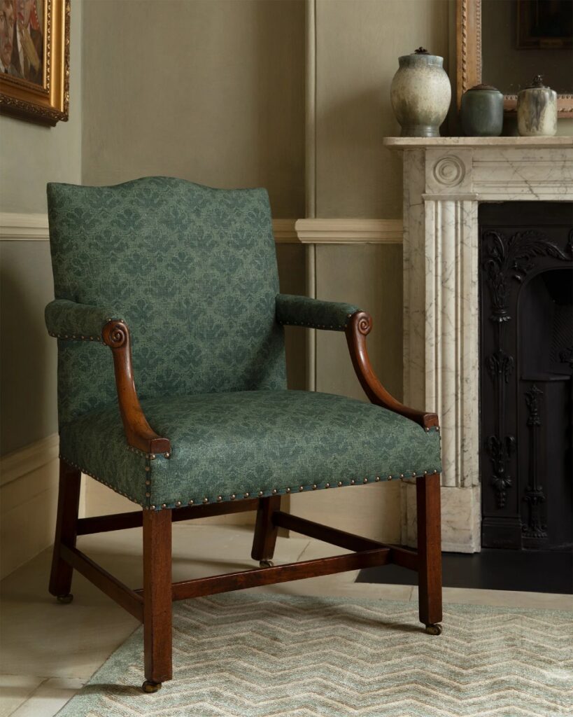 A roll of Chelsea Textiles Havisham fabric in seafoam, featuring a distressed floral print on a cotton and hemp blend to evoke a vintage, Dickensian aesthetic.