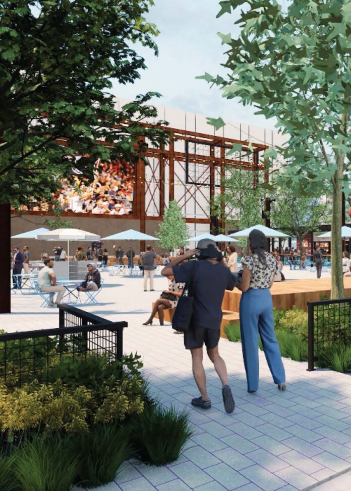 Two people watch the large screen at The Plaza at North Shore with tables around them.