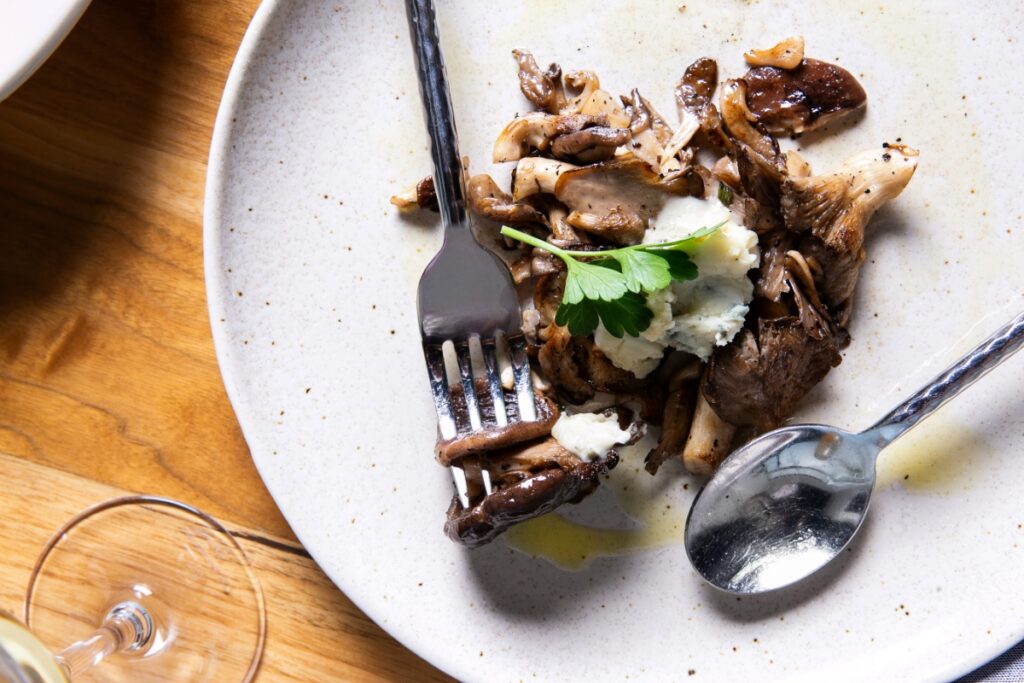 A gourmet plate of three large spicy meatballs topped with tomato sauce, melted cheese, and fresh herbs at Vivo Kitchen in Sewickley.