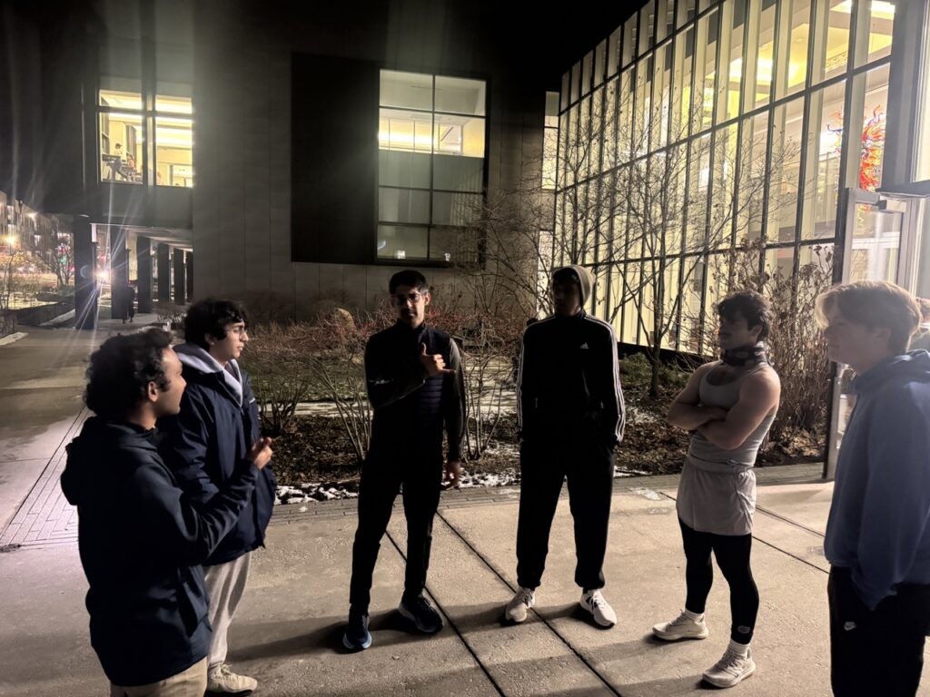 Six runners talk in a circle at night.