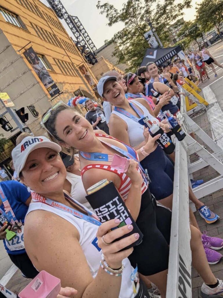 Four women in work out clothes hold waters at a starting line.