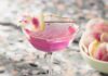 Watermelon Radish Martini A tall pink martini cocktail with a watermelon radish on a tooth pick as a garnish.
