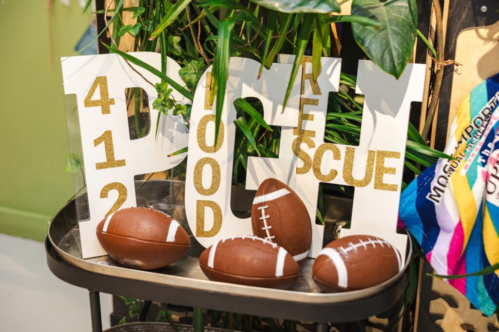 A chair with footballs and a sign behind them the says 412 Food Rescue, a decoration for a post NFL Draft dinner held by the organization. 