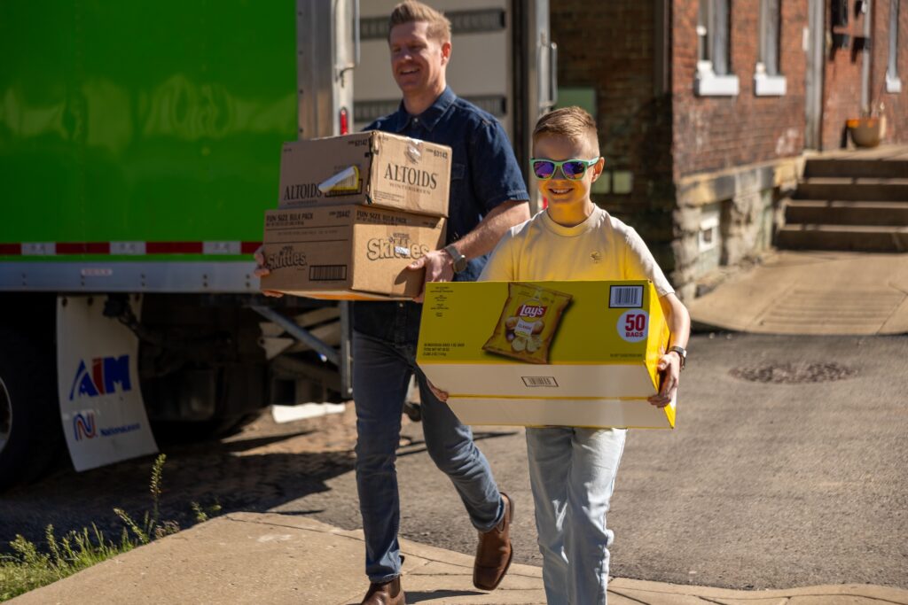A man and a young boy carrying boxes off of a 412 Food Rescue truck of rescued food.
