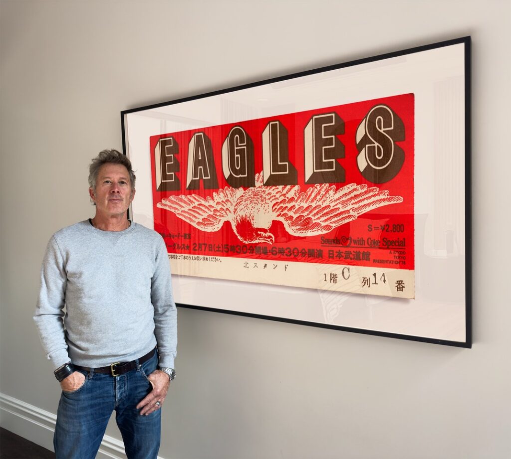 Blaise Hayward stands in front of a photo of an Eagles ticket he took.