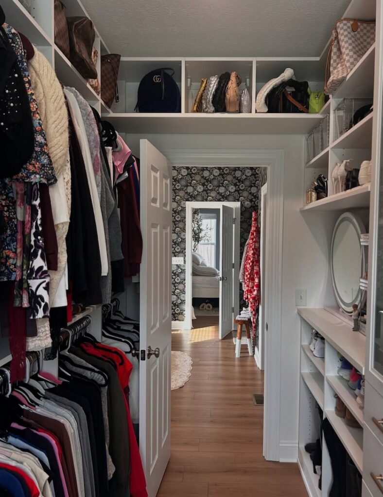 The inside of California Closets show room with clothes hung up in a closet space and shoes on shelves.