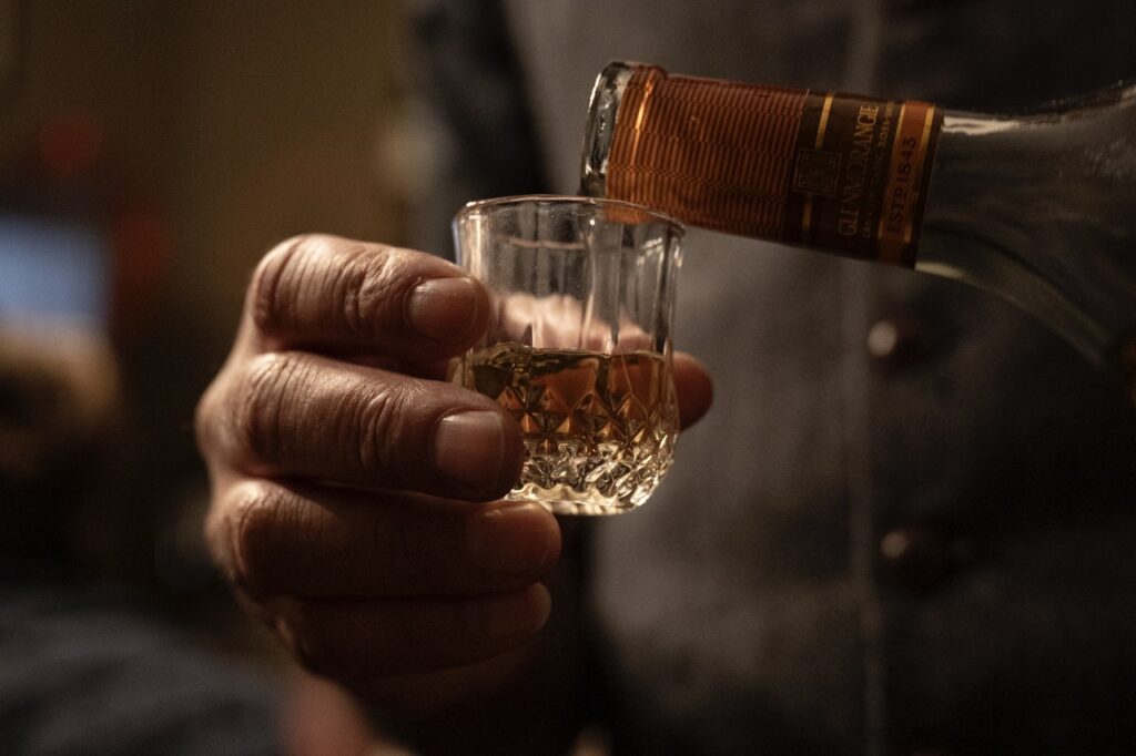 A man pours scotch into a small glass.