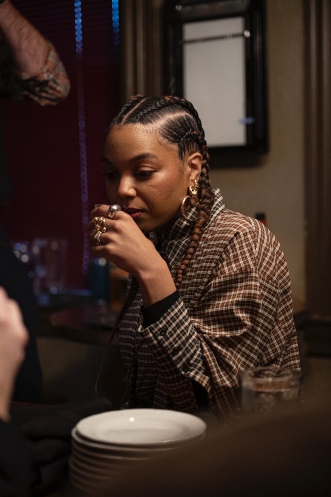 A woman in a pattern jacket smells a small sample of scotch.