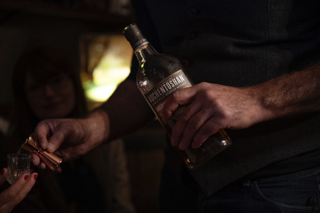 A man holds a bottle of scotch.