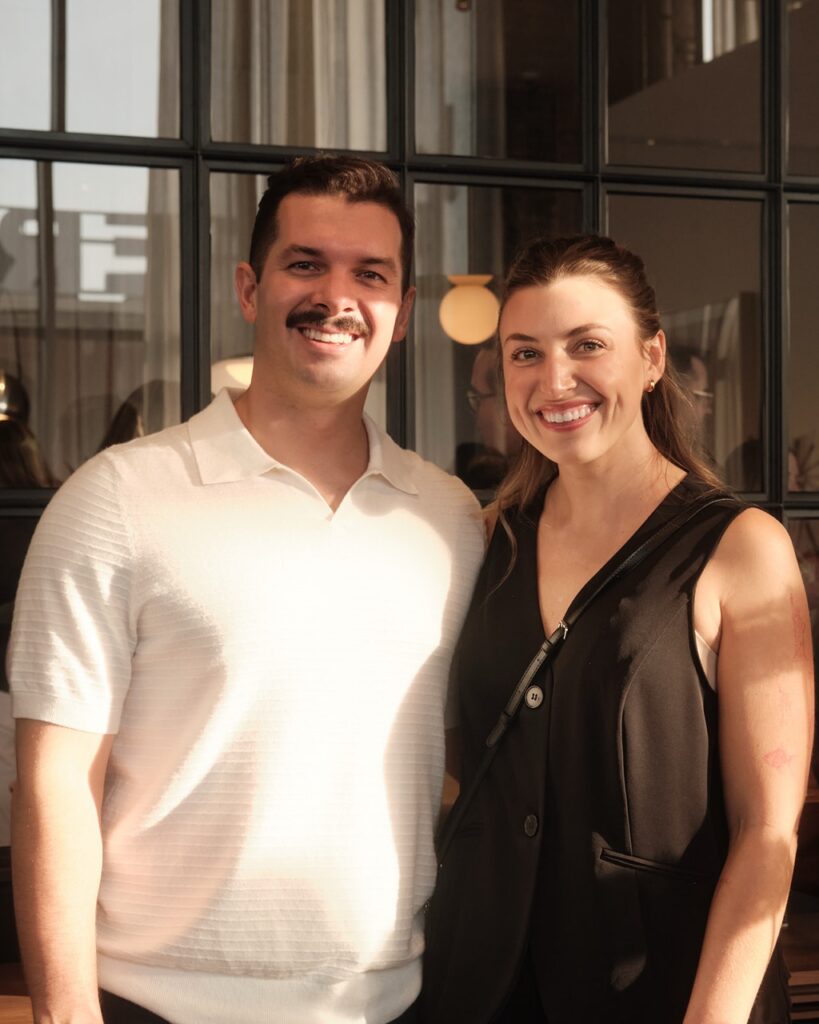 A man in a white shirt smiles with a woman in a black vest.