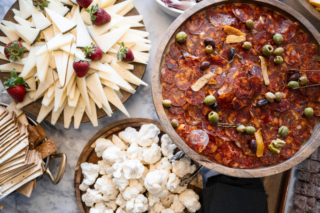 A tray full of cheese, a tray full of pepperoni, and a tray full of cauliflower.