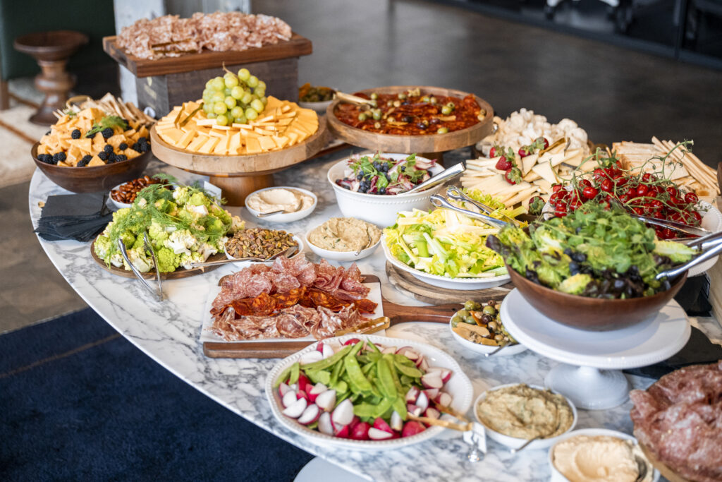 A table full of cheese, meats, and vegetables.