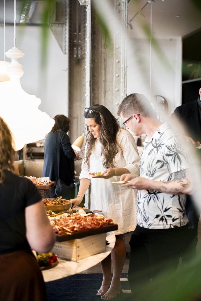 A man and woman fill small plates with charcuterie.