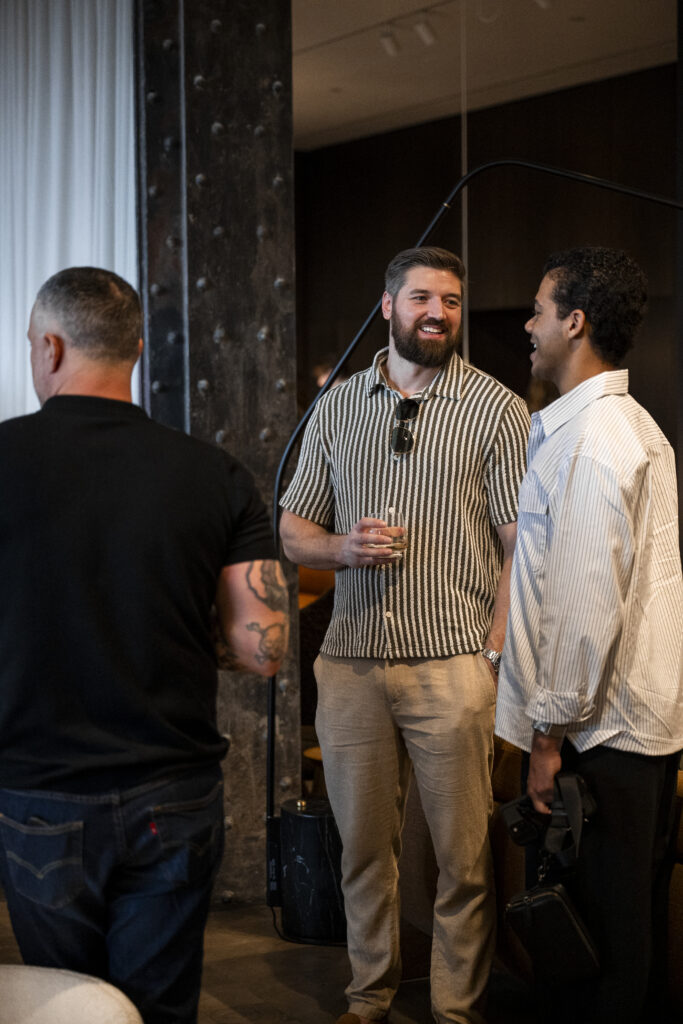 Two men in striped button-up shirts talk together.