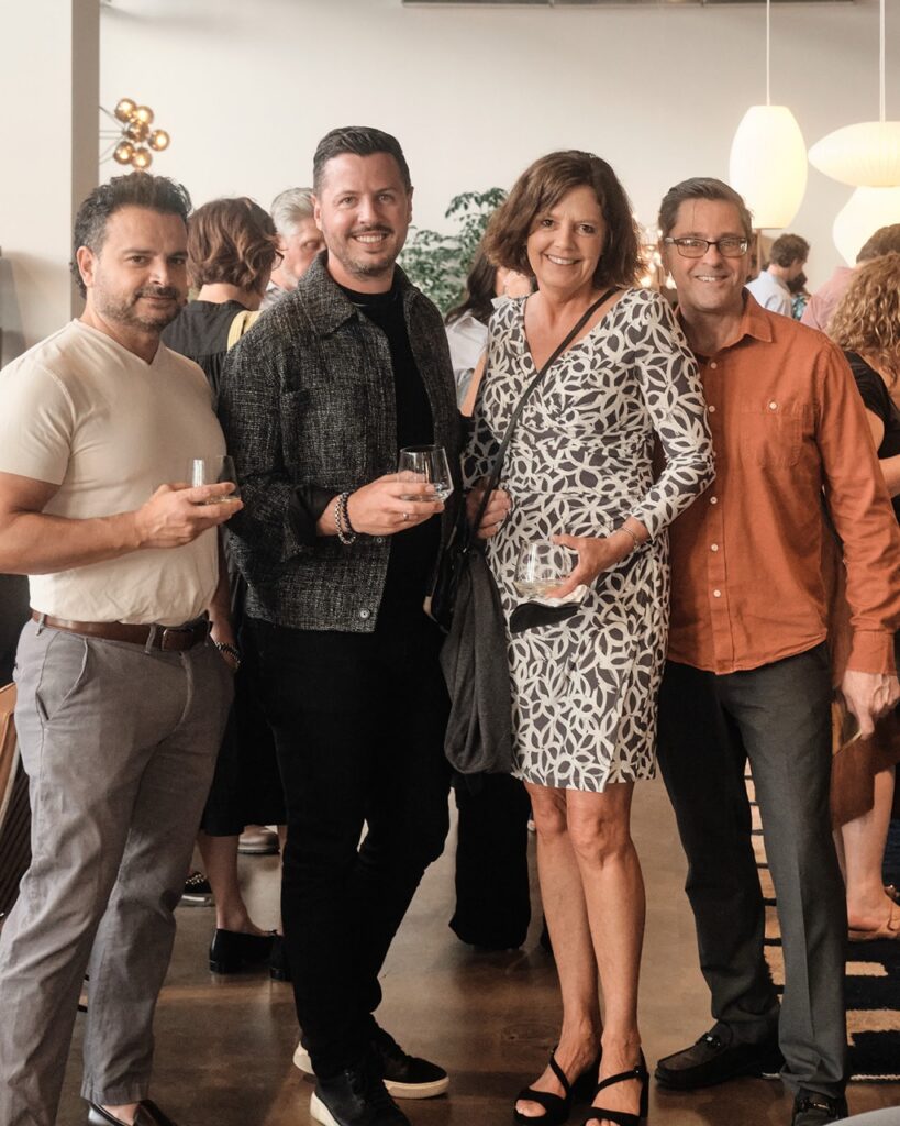 Three men and a woman in a dress stand together in a showroom space.