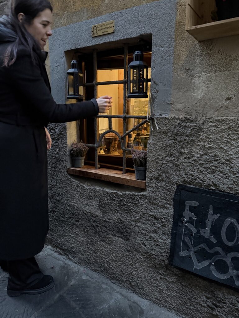 A woman shows off a wine window in Florence.