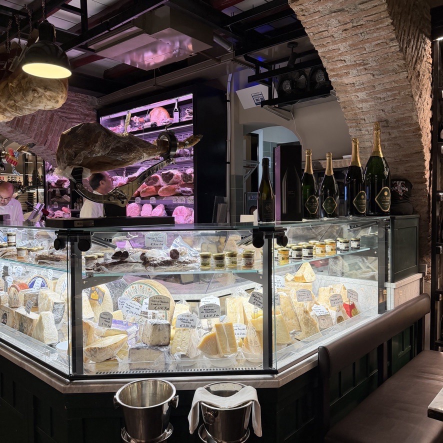 A cheese counter case filled with various cuts of cheese in Rome.