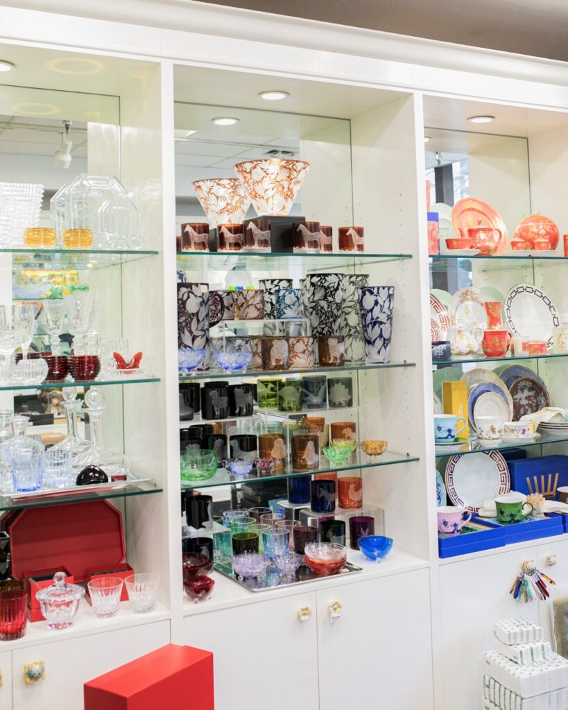 Three shelves full of colorful glass and porcelain tableware.