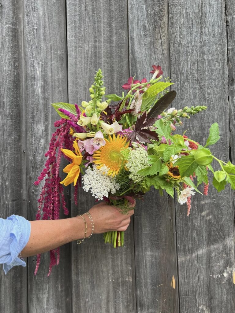 A woman holds a bouquet of photos in front of a dark wood wall.