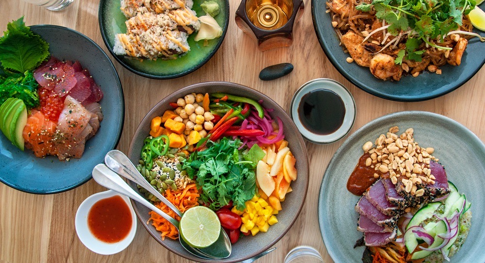 A table full of food on different blue plates all on a wood table.