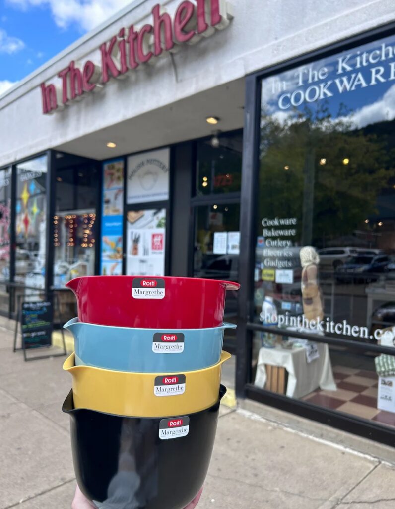 A stack of mixing bowls in different colors are held outside of In The Kitchen