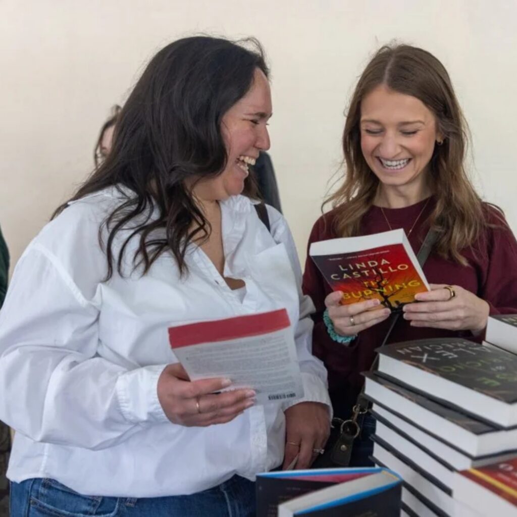 Two women pick up books at the PGH Book Fest. 