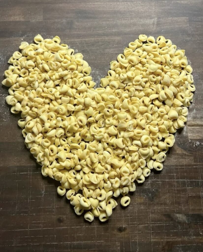Handmade pasta on a table in the shape of a heart. 