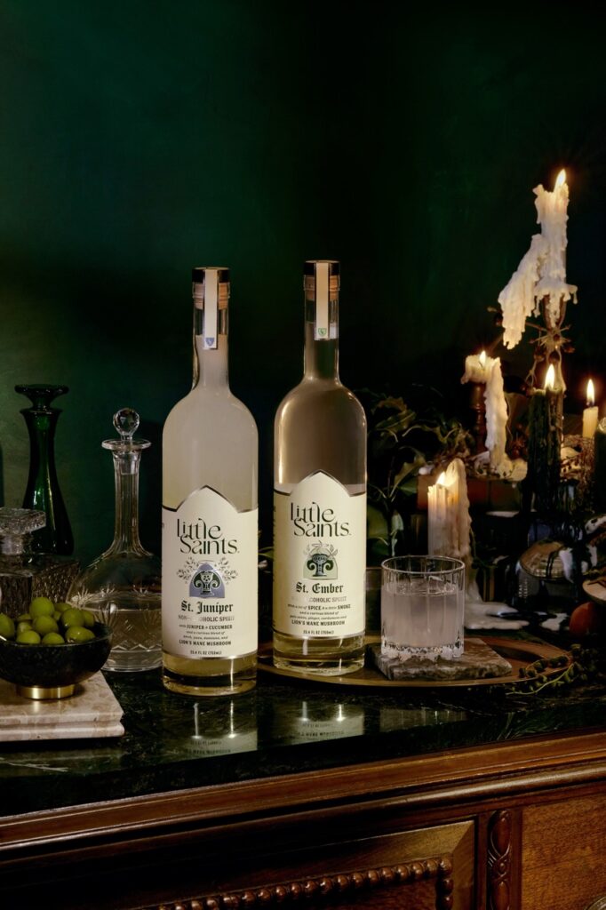 Two bottles of Little Saints spirits sit on a food table.