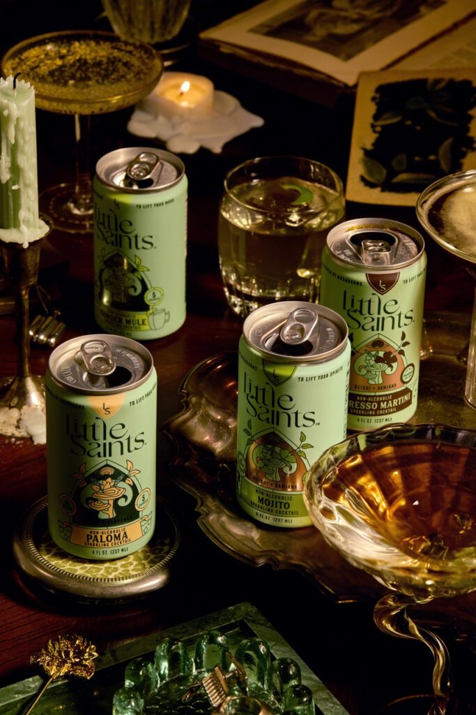 Cans of Little Saints non-alcoholic cocktails on a table in green.