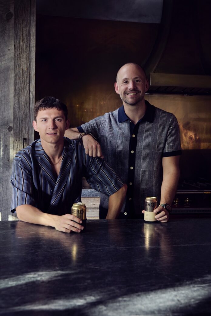 Tom Holland and the other co-founder of BERO stand beside each other holding cans of non-alcoholic beer.