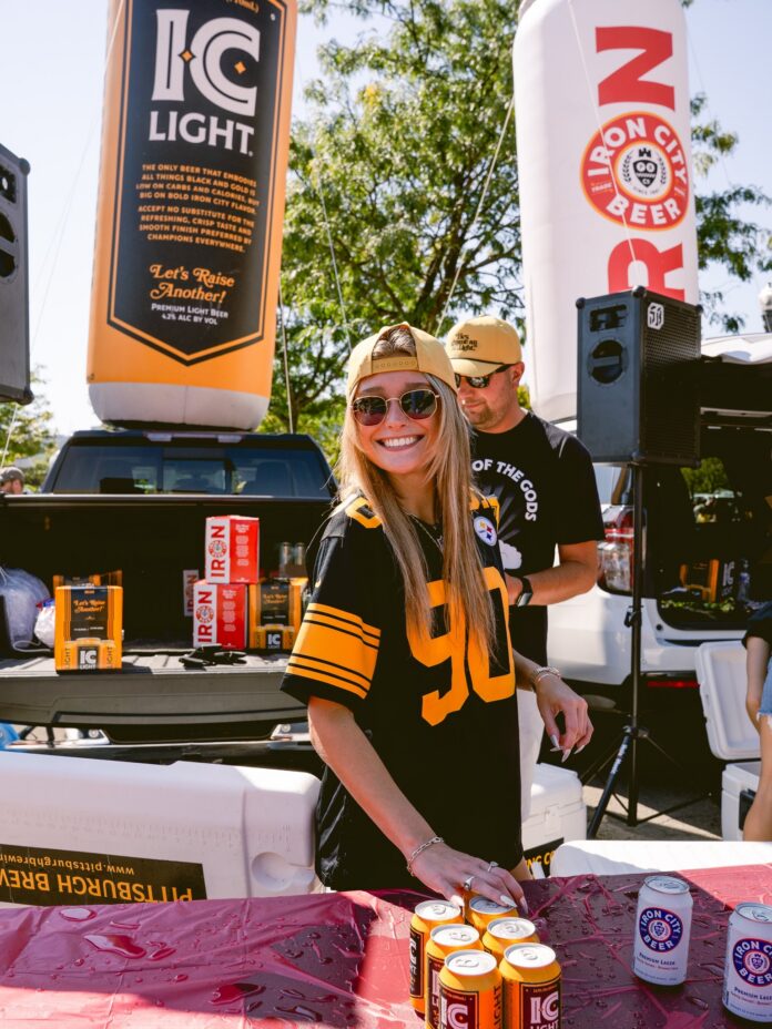 NFL Draft Events TABLE Magazine A woman in a Steelers NFL jersey stands behind a table of Iron City Light beer.