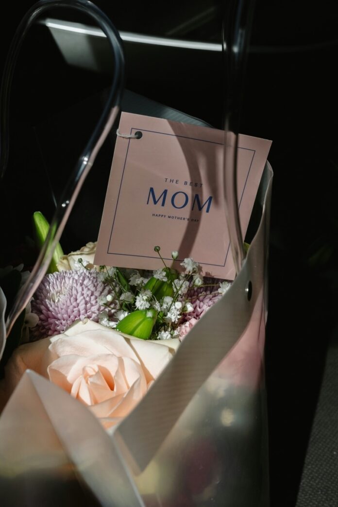 A gift bag with flowers and a note for mom about Mother's Day inside.