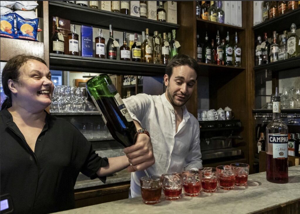 A man pours glasses of cocktails at a Florence bar.