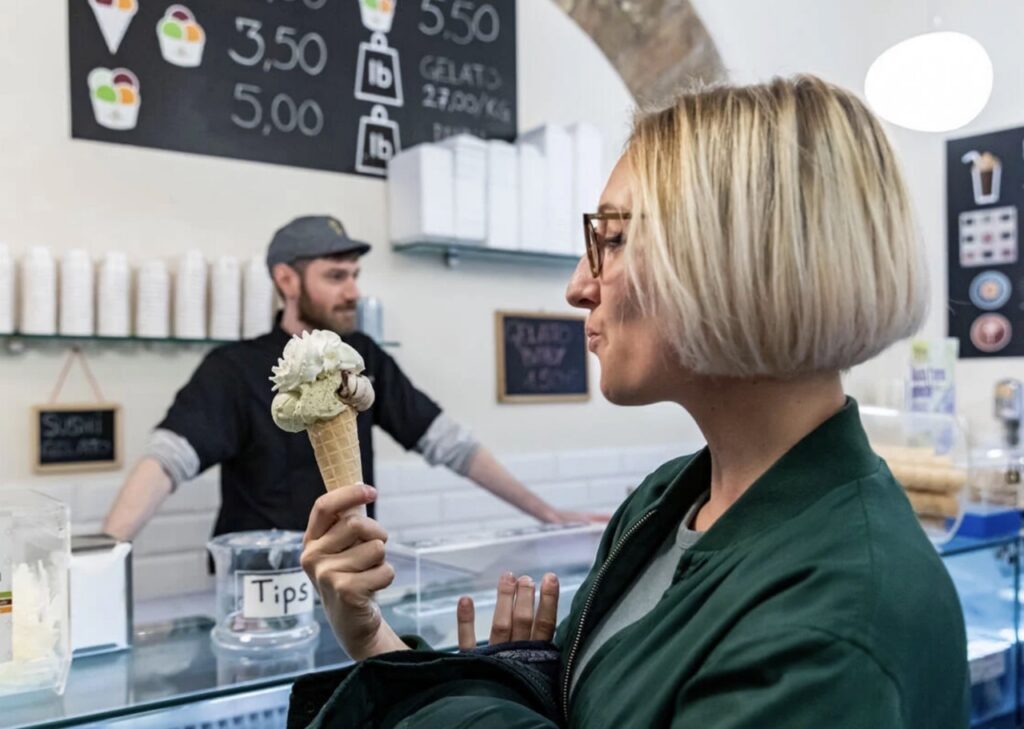 A woman looks at a scoop of vanilla ice cream.