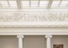 The 59th Carnegie International Rewards Looking Up in 2026’s Exhibition A white corridor with columns and marble statues behind a guard rail.