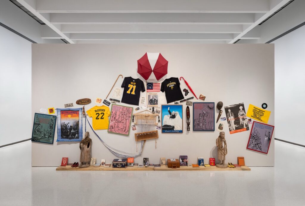 A white wall full of pictures and sports jerseys.