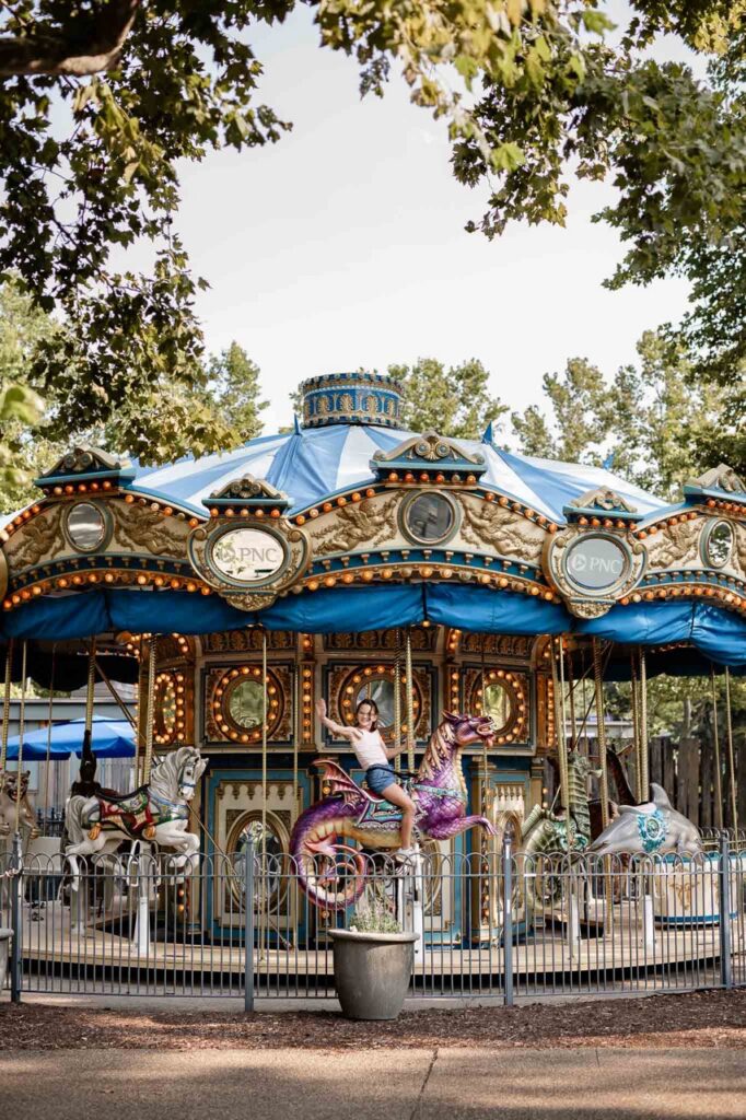 A girl waves on a carousel in Pittsburgh's Schenley Plaza park.