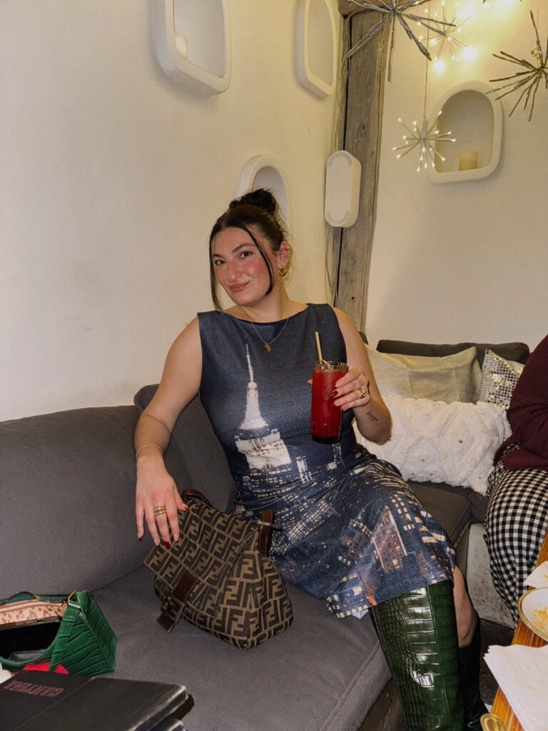 Hungry Jess sits on a grey couch at Esquina Cantina in Pittsburgh in a long dress. 