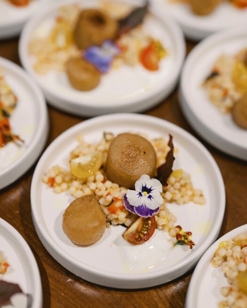 Small plates of a scallop appetizer dish garnished with violet flowers.