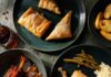 Cultural Cuisine Around Pittsburgh From the Middle East to France A table full of cultural cuisine dishes on green plates like chicken and rice, greek pastries, and African beef.
