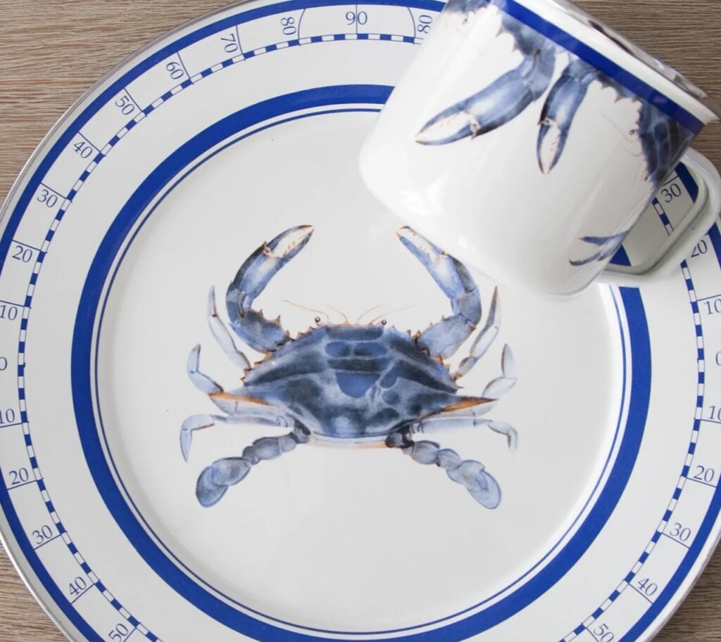 A white plate set with a blue crab on it.