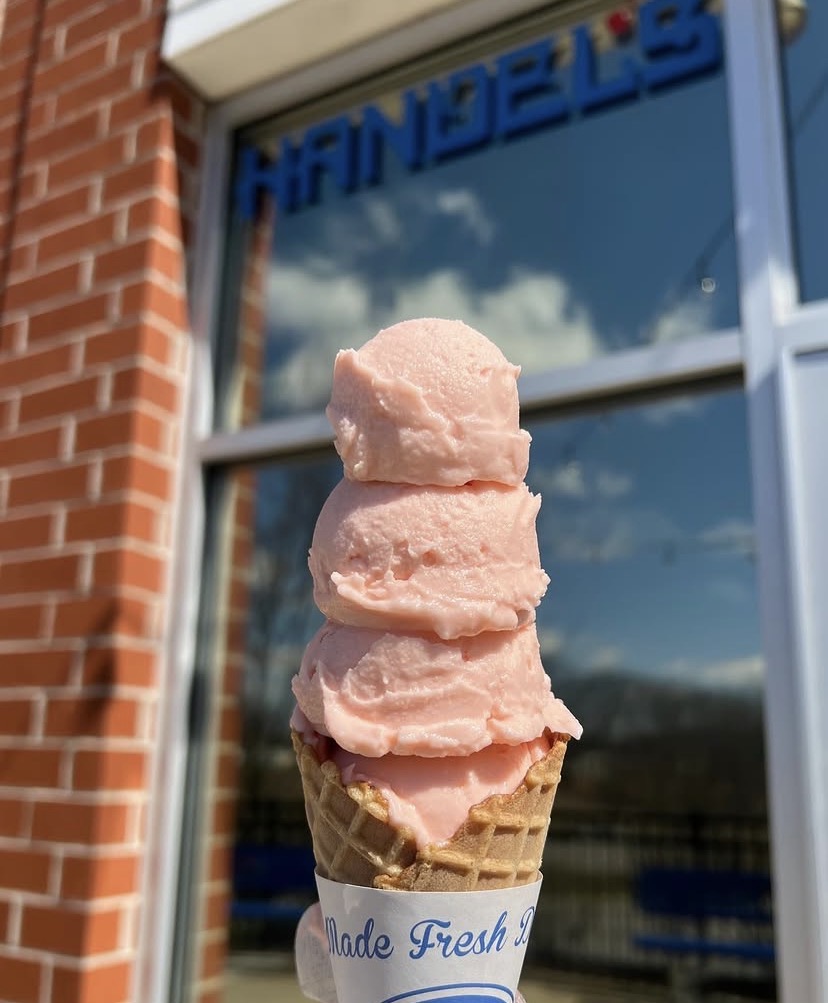 A pink colored ice cream in a sugar cone.