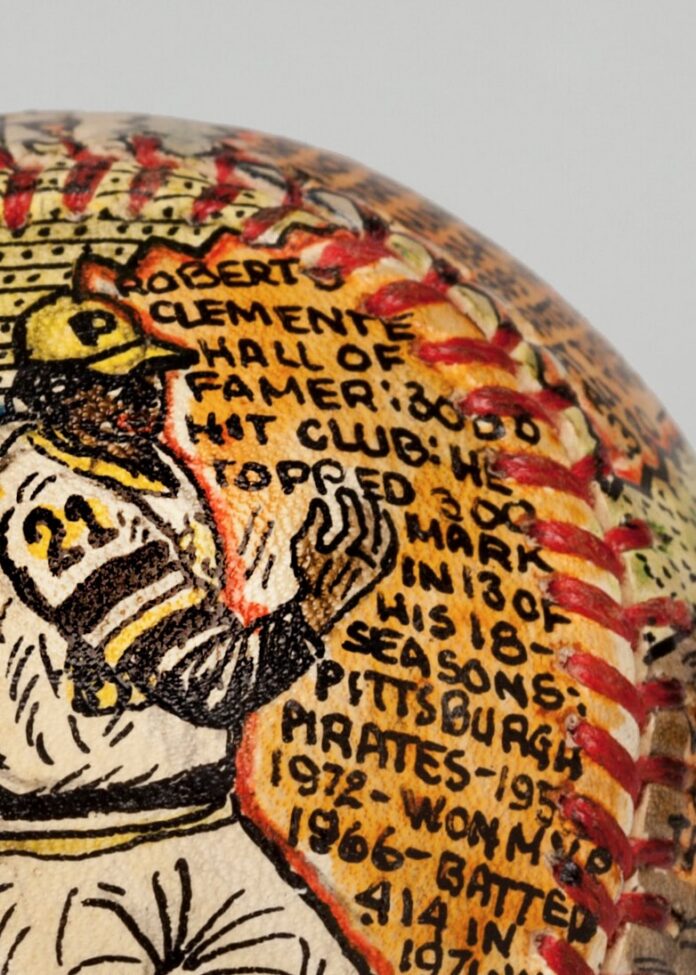 A Roberto Clemente baseball with a painting of him on it and writing about him.