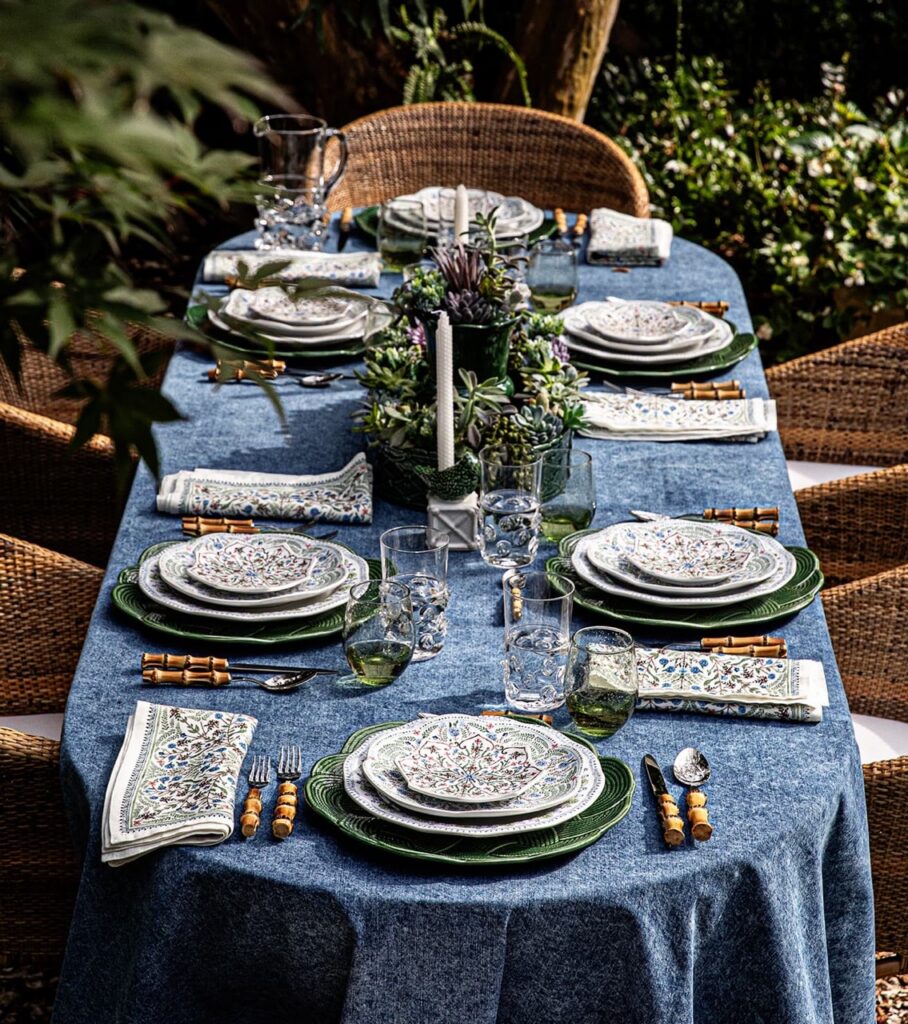 A blue table setting with white stacks of plates on the table.