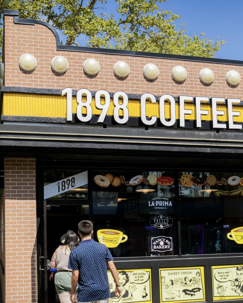 Two people enter a coffee shop.
