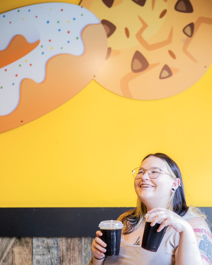 A woman holding two cups of coffee.