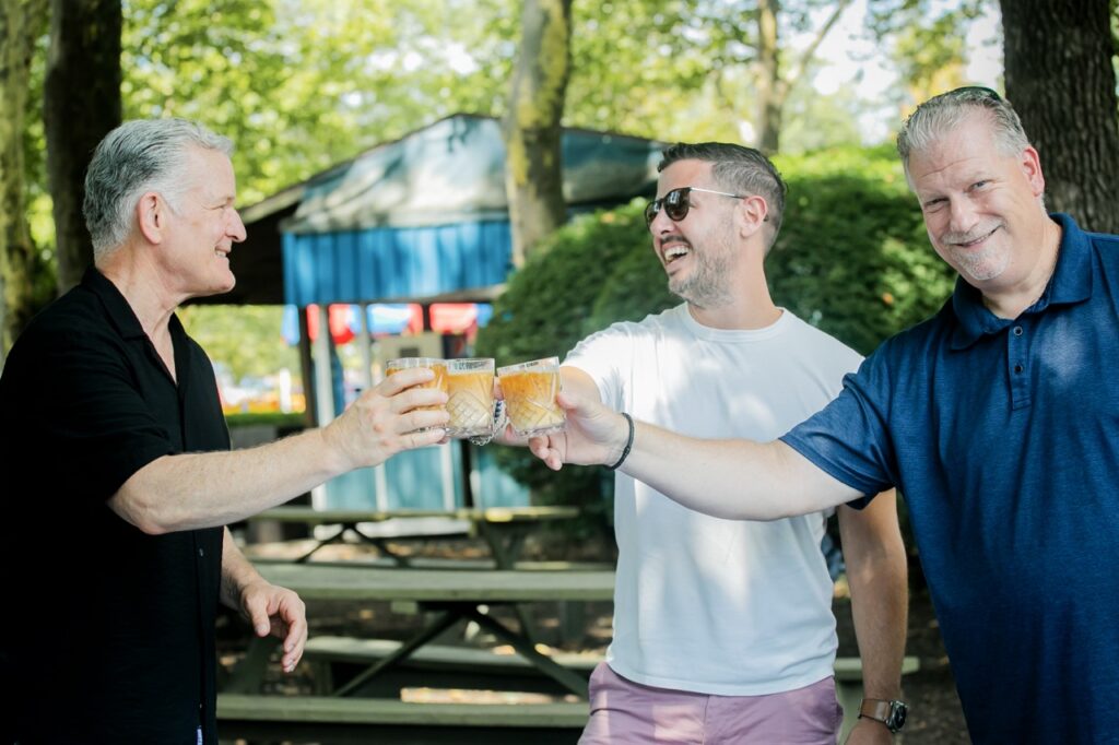 Three men cheers and smile with coffee mocktails.
