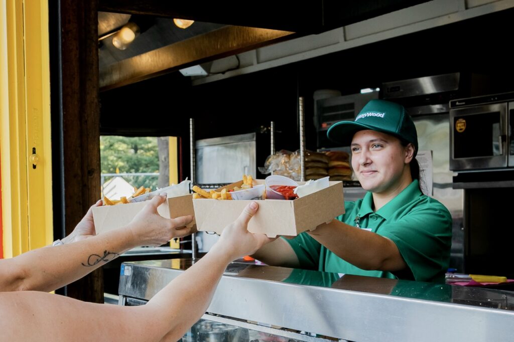 A woman hands over two boxes of food.